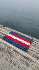 Five Stripe Rope Woven Mat, Navy Blue, Red, and White displayed on a dock
